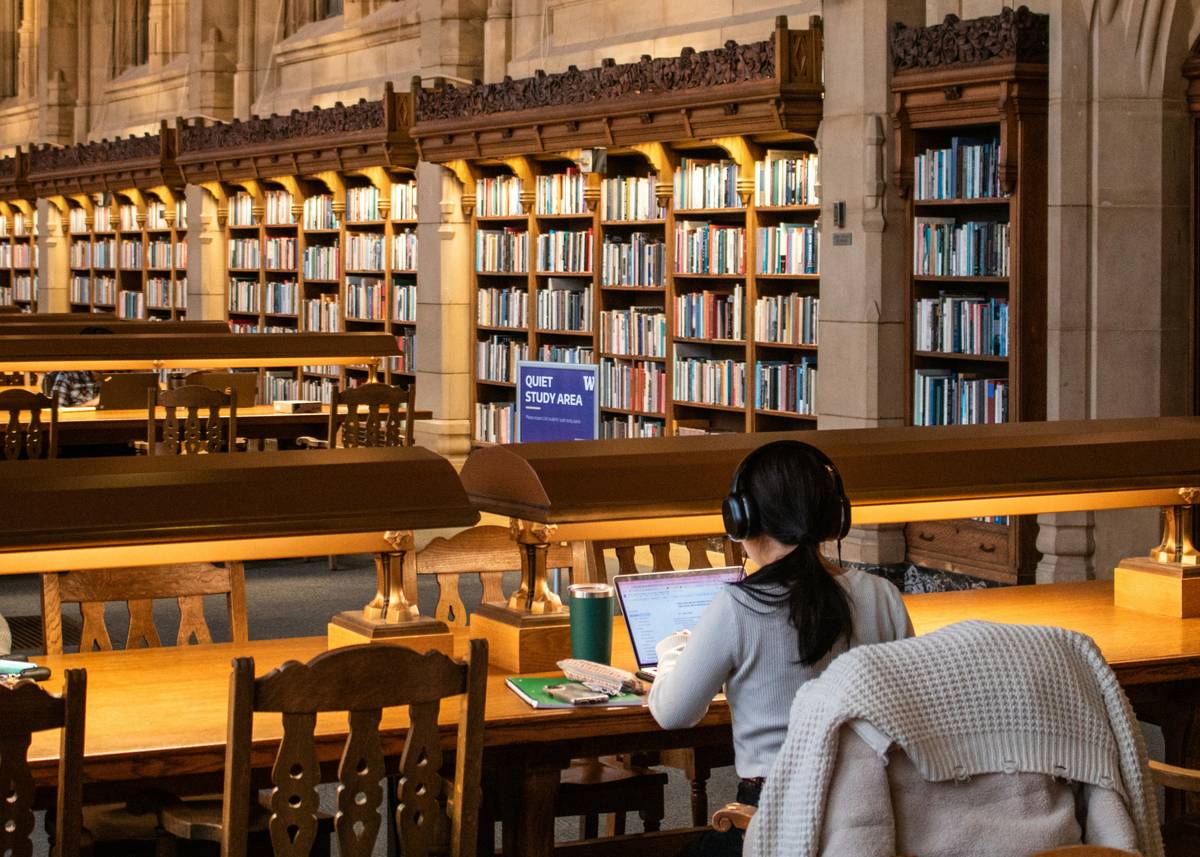 Photo of a stressed student surrounded by books and highlighting a textbook.